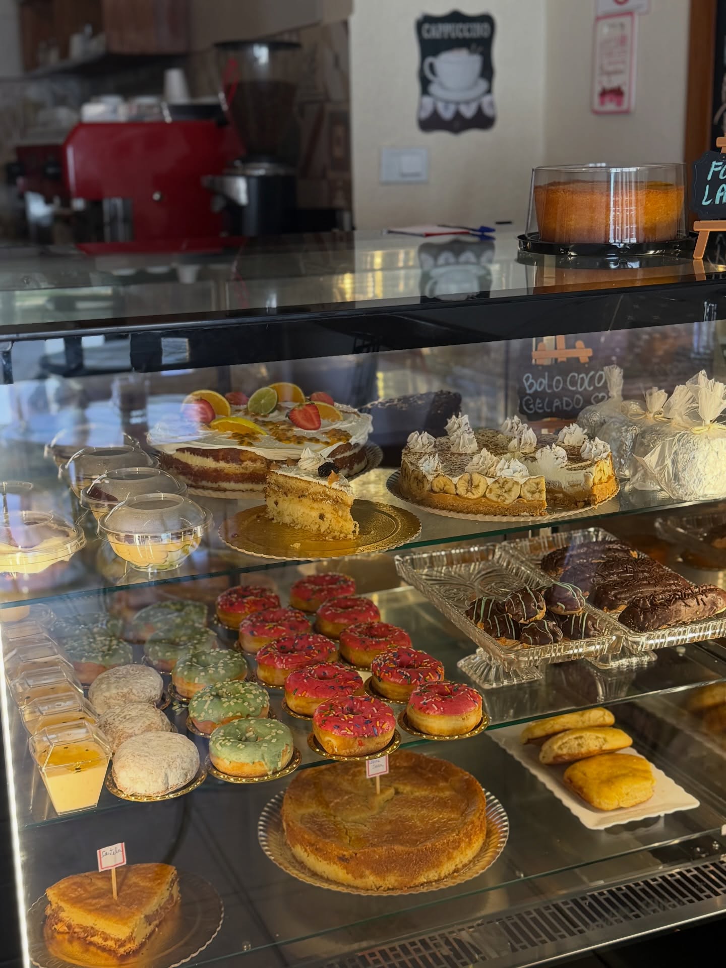 Vitrine com bolos, donuts, tortas e doces variados